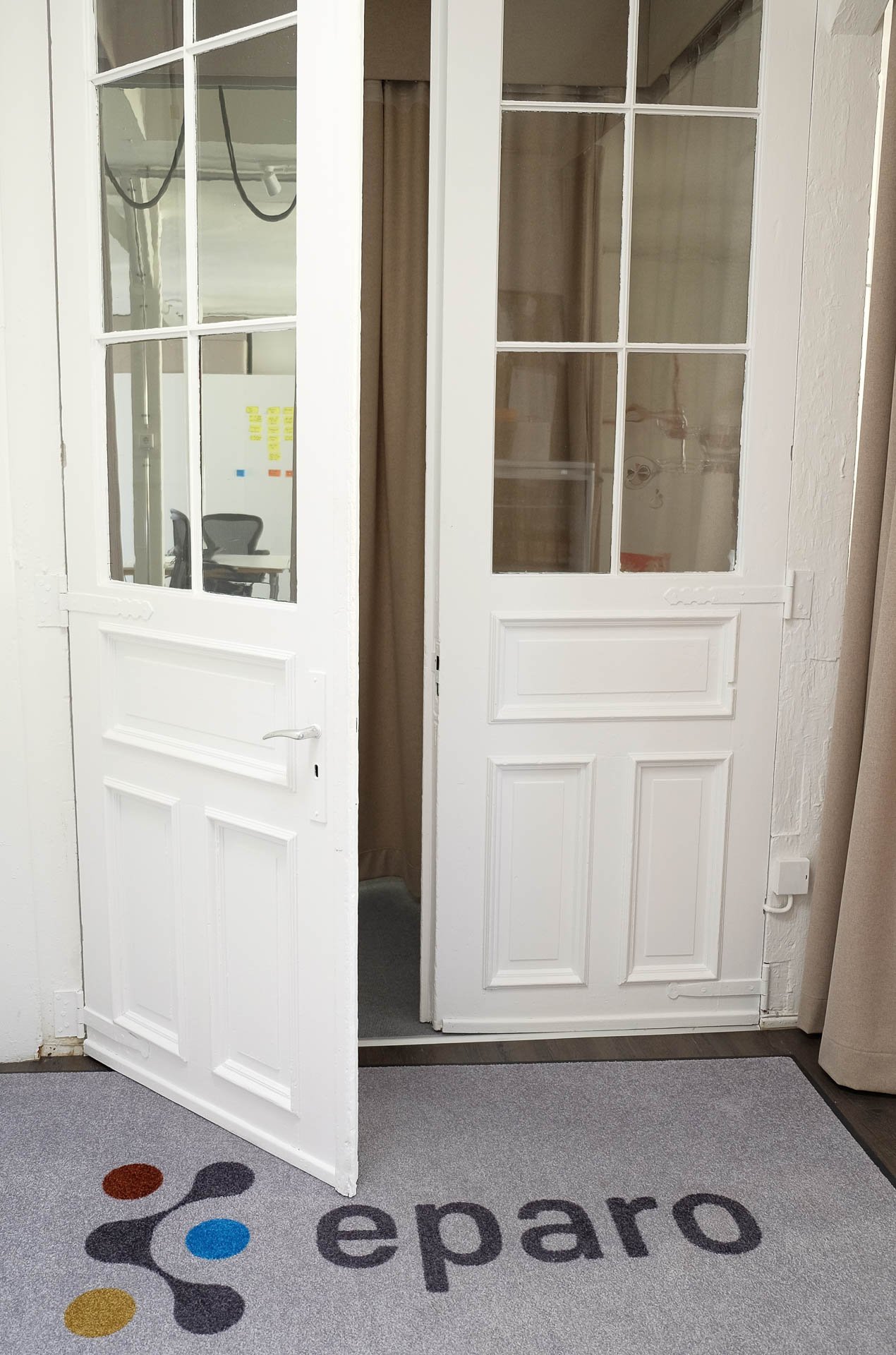 weiße Tür zum Workshopraum mit eparo logo auf grauen Teppich